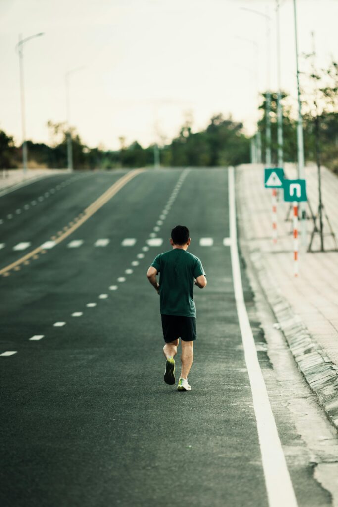 Rear view of a man jogging on an empty road in Kon Tum, Vietnam.